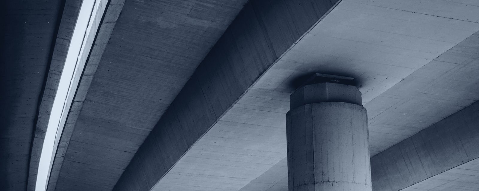 Underside of a concrete overpass in slate duotone — atmospheric imagery
